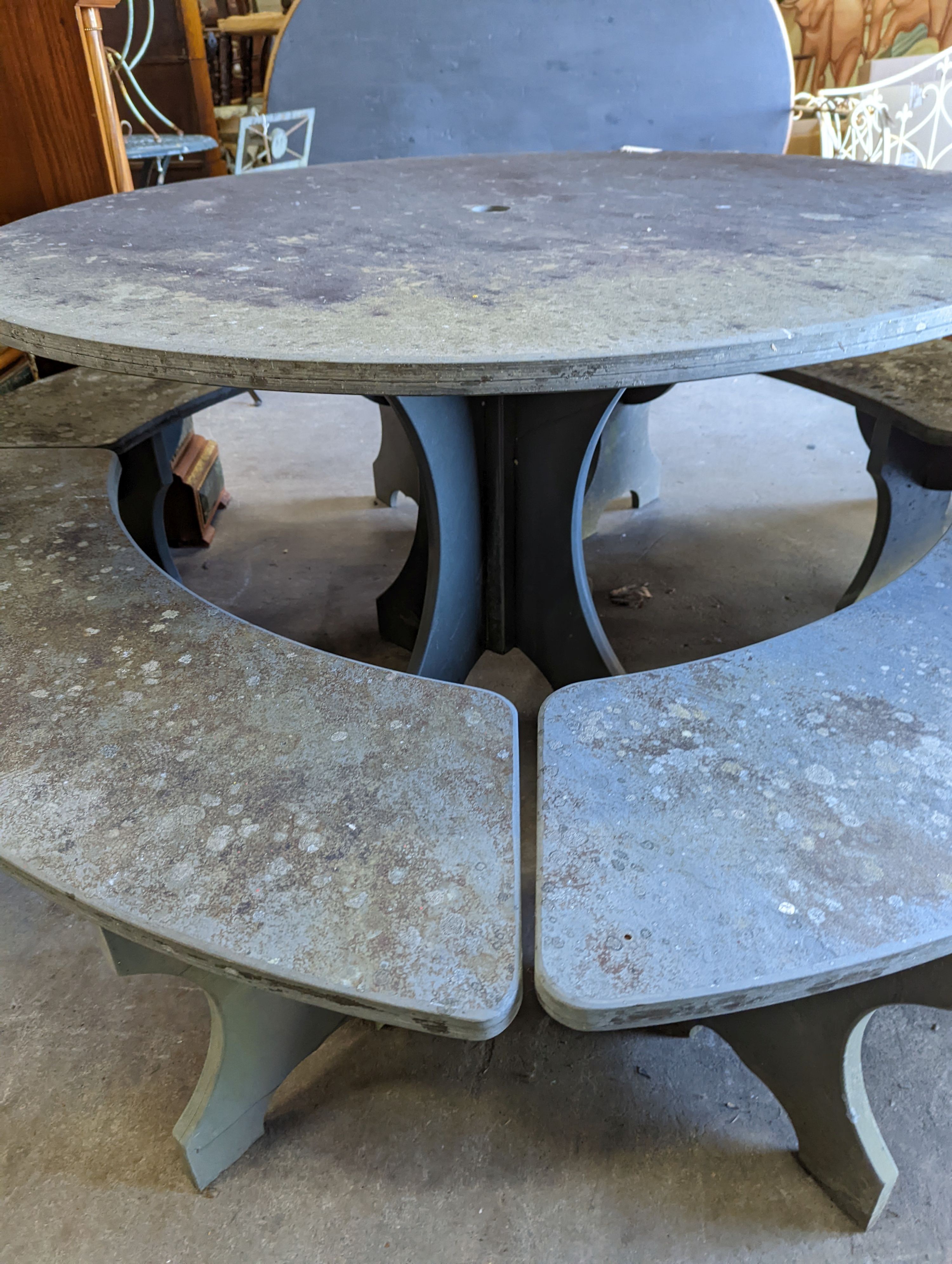 A heavy slate circular topped garden table, diameter 125cm, height 79cm together with four crescent shaped slate garden benches